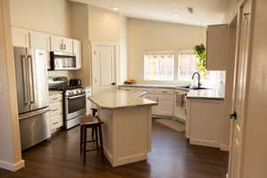 Kitchen with a center island, stainless steel appliances, white cabinetry, and sink