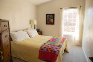 Bedroom with carpet floors, vaulted ceiling, and multiple windows