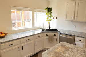 Kitchen featuring white cabinetry, dishwasher, a healthy amount of sunlight, and sink