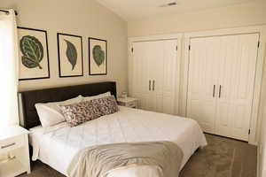 Master Bedroom with dark carpet, lofted ceiling, and two closets