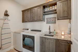 Washroom with cabinets, washing machine and dryer, and sink