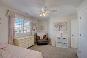 Carpeted bedroom featuring ceiling fan