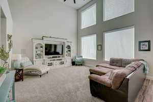 Living room featuring ceiling fan and a towering ceiling