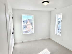 Spare room featuring a healthy amount of sunlight and light carpet