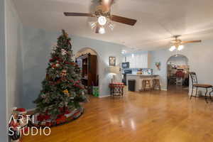 Living room with light hardwood / wood-style flooring, ceiling fan, and lofted ceiling