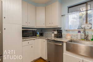 Kitchen featuring light stone counters, sink, and stainless steel appliances