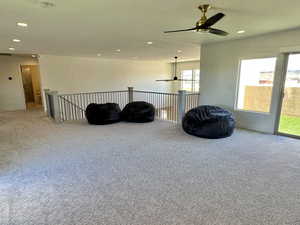 Living area with carpet floors and ceiling fan, view of hallway and guest bathroom