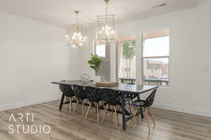 Dining space with a wealth of natural light, hardwood / wood-style floors, and an inviting chandelier