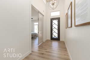 Entrance foyer featuring light hardwood / wood-style flooring and a notable chandelier with wood paneled ceiling