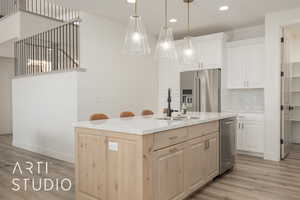 Kitchen with hanging light fixtures, tasteful backsplash, light brown cabinetry, a center island with sink, and appliances with stainless steel finishes