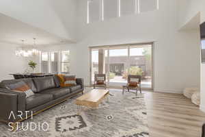 Living room featuring a towering ceiling, light hardwood / wood-style floors, a healthy amount of sunlight, and ceiling fan