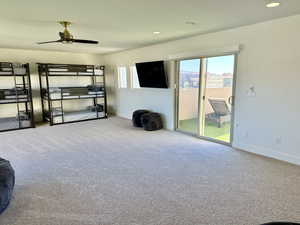 Carpeted living room with ceiling fan, view of West facing deck