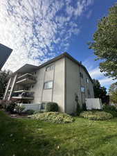 View of property exterior with a lawn and a balcony