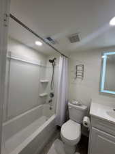 Full bathroom featuring shower / bath combo with shower curtain, vanity, hardwood / wood-style floors, and toilet