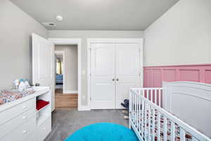 Carpeted bedroom with a closet and a crib