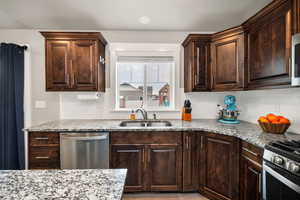 Kitchen featuring light stone countertops, sink, appliances with stainless steel finishes, and tasteful backsplash