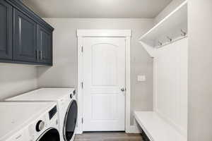 Clothes washing area featuring separate washer and dryer, dark hardwood / wood-style flooring, and cabinets