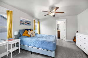 Carpeted bedroom featuring ceiling fan and ensuite bathroom