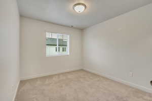 Unfurnished room with a textured ceiling and light carpet