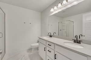 Bathroom featuring a shower with door, vanity, a textured ceiling, and toilet