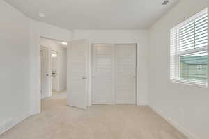 Unfurnished bedroom featuring light carpet and a closet