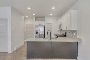 Kitchen with white cabinetry, sink, kitchen peninsula, and stainless steel appliances