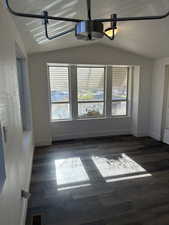 Unfurnished room with a textured ceiling, vaulted ceiling, and dark wood-type flooring