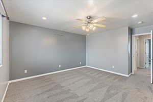 Spare room featuring light carpet, a textured ceiling, and ceiling fan