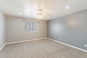 Carpeted empty room featuring a textured ceiling and ceiling fan