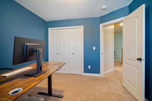 Carpeted home office featuring a textured ceiling