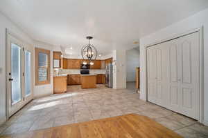 Kitchen featuring stainless steel fridge, decorative light fixtures, a kitchen island, and light tile patterned flooring