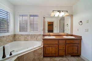 Bathroom with vanity, tile patterned floors, and tiled tub