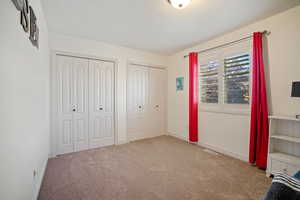 Unfurnished bedroom featuring carpet flooring and multiple closets