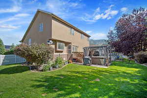 Back of property with a lawn, a pergola, and a hot tub