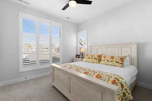 Bedroom with light colored carpet and ceiling fan, plantation shutters & views.