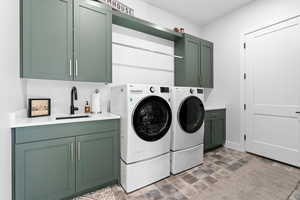 Laundry room with washer and clothes dryer, cabinets, and sink