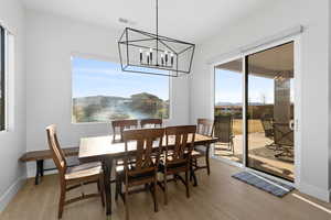 Dining space with a notable chandelier and light hardwood / wood-style flooring, sliding glass door.