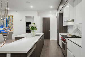 Kitchen with white cabinetry, a center island, premium stove, decorative backsplash, and dark brown cabinets