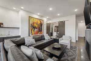 Living room featuring a barn door, dark hardwood / wood-style floors, and wet bar