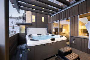 Snow covered patio featuring a hot tub