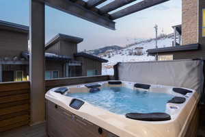 Snow covered patio featuring a deck with mountain view and a hot tub