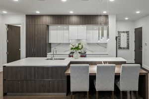 Kitchen featuring white cabinets, stove, sink, and a kitchen island with sink