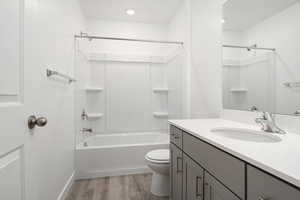 Full bathroom featuring hardwood / wood-style floors, vanity, toilet, and shower / tub combination