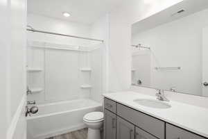 Full bathroom featuring hardwood / wood-style floors, vanity, toilet, and bathing tub / shower combination