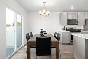 Dining space with light hardwood / wood-style flooring and a chandelier