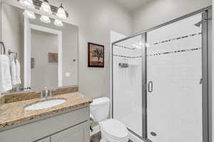 Bathroom featuring vanity, toilet, and a shower with door