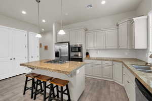 Kitchen with pendant lighting, a kitchen island, white cabinetry, and stainless steel appliances