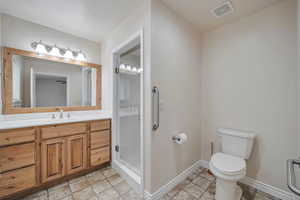 Bathroom featuring walk in shower, vanity, and toilet