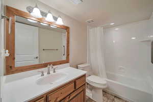 Full bathroom with vanity, shower / bath combination with curtain, and toilet