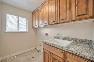 Laundry area featuring electric dryer hookup, cabinets, sink, and hookup for a washing machine